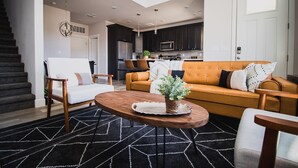 Una sala de estar moderna con un sofá, sillones y una mesa de centro.