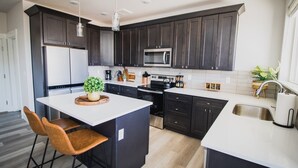 Una cocina moderna con armarios oscuros, una isla central y un lavaplatos de acero inoxidable.