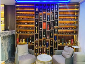 A bar area with a wine and liquor display, two armchairs, a small round table, and a marble countertop. - LINTOC HOTEL & SUITES LTD (Enugu)