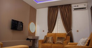 Un salon moderne comprenant un canapé, une table basse, un téléviseur fixé au mur et un appareil de climatisation.
