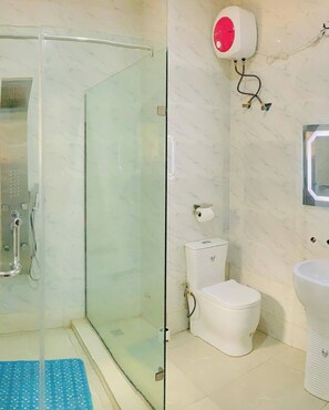 Une salle de bain avec une douche à parois de verre, des toilettes et un lavabo.
