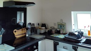 Cozinha com teto de madeira, bancada preta, armários brancos e janela com vista.