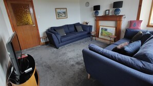 Uma sala de estar com um sofá azul, uma televisão e uma lareira.
