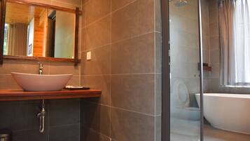 Un baño moderno con un lavamanos grande tipo recipiente, una bañera independiente y una ducha con cerramiento de vidrio.