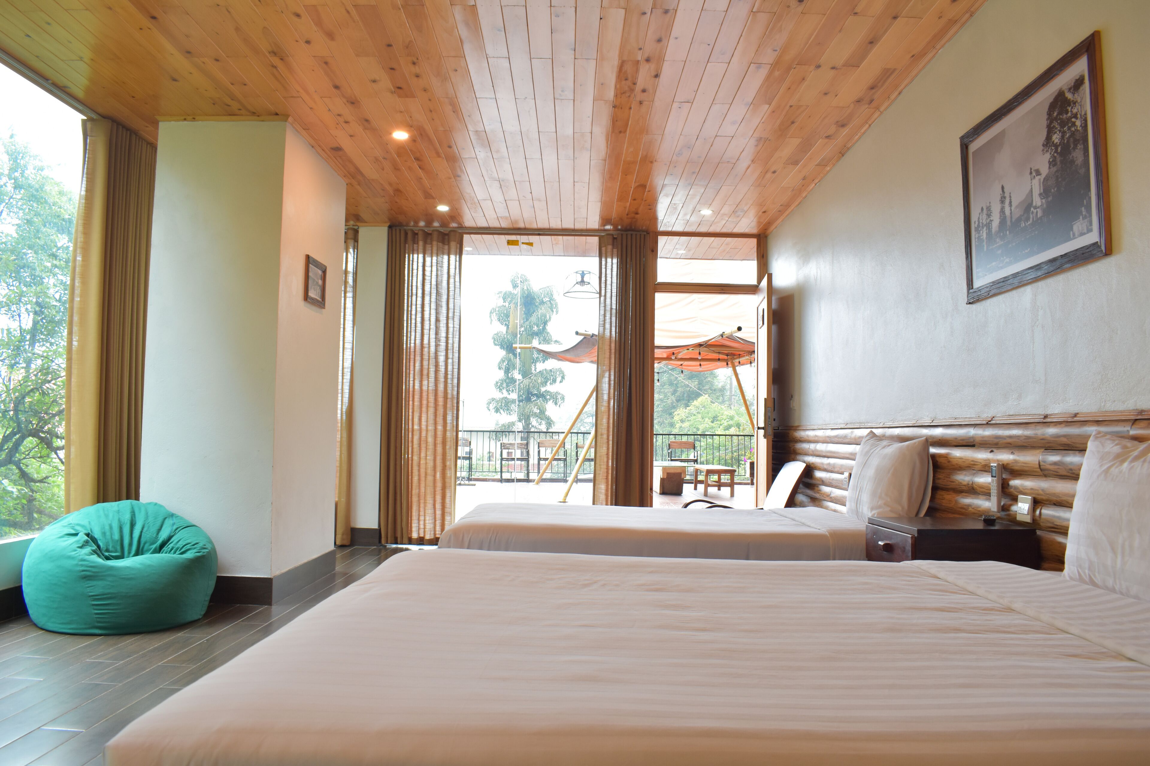 Un dormitorio con dos camas, techo de madera y balcón con sombrilla.