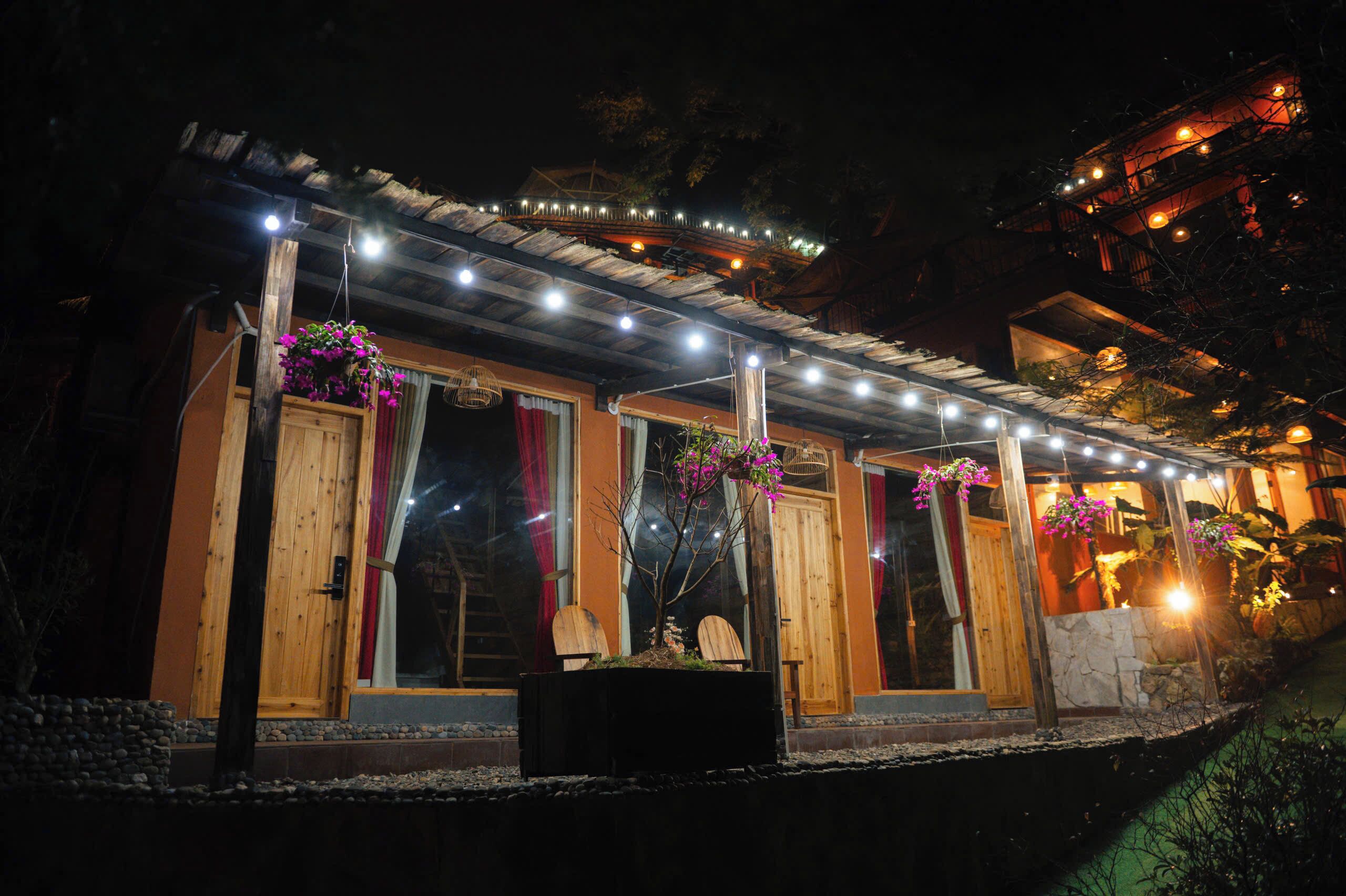 A building with a covered porch, wooden doors, and hanging flower baskets.