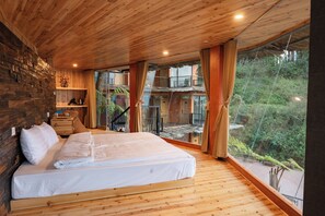 A bedroom with a wooden ceiling, a large bed, a stone wall, and a view of a balcony with greenery. - Sapa Chill Retreat (Sa Pa)