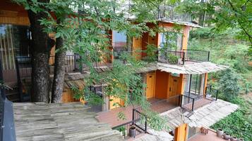 A multi-story wooden building with balconies, surrounded by trees.