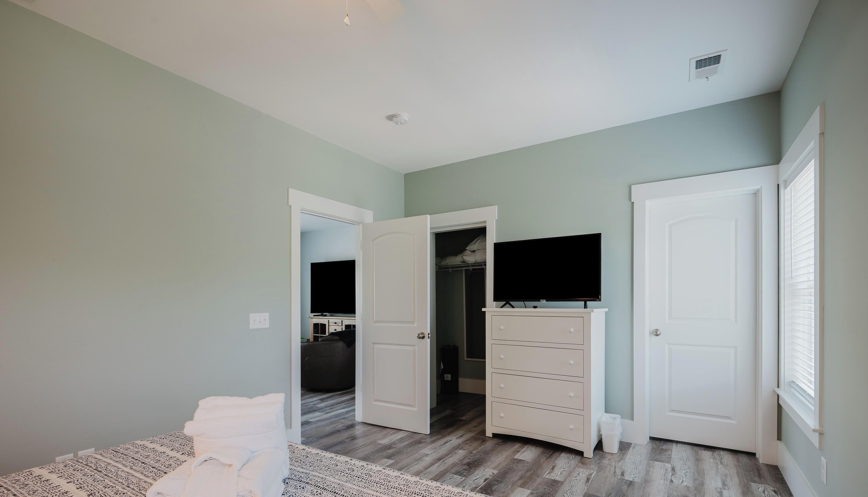 Een slaapkamer met een bed, een dressoir, een kast en een televisie.