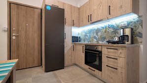 Une cuisine avec des meubles de rangement en bois, un réfrigérateur, un four à micro-ondes, un four et une machine à café.