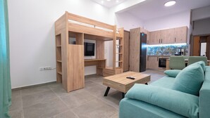 Un espace de vie moderne comprenant un lit superposé, un canapé, une table basse et un coin cuisine.