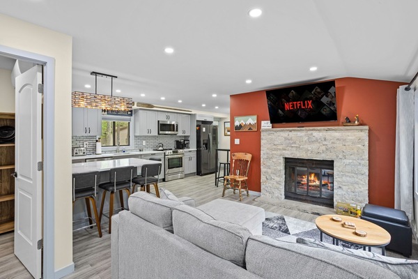Sink into the plush sectional and unwind by the warm glow of the fireplace. With an open-concept design, modern kitchen, and a big-screen TV for endless entertainment, this space is perfect for both relaxation and socializing.