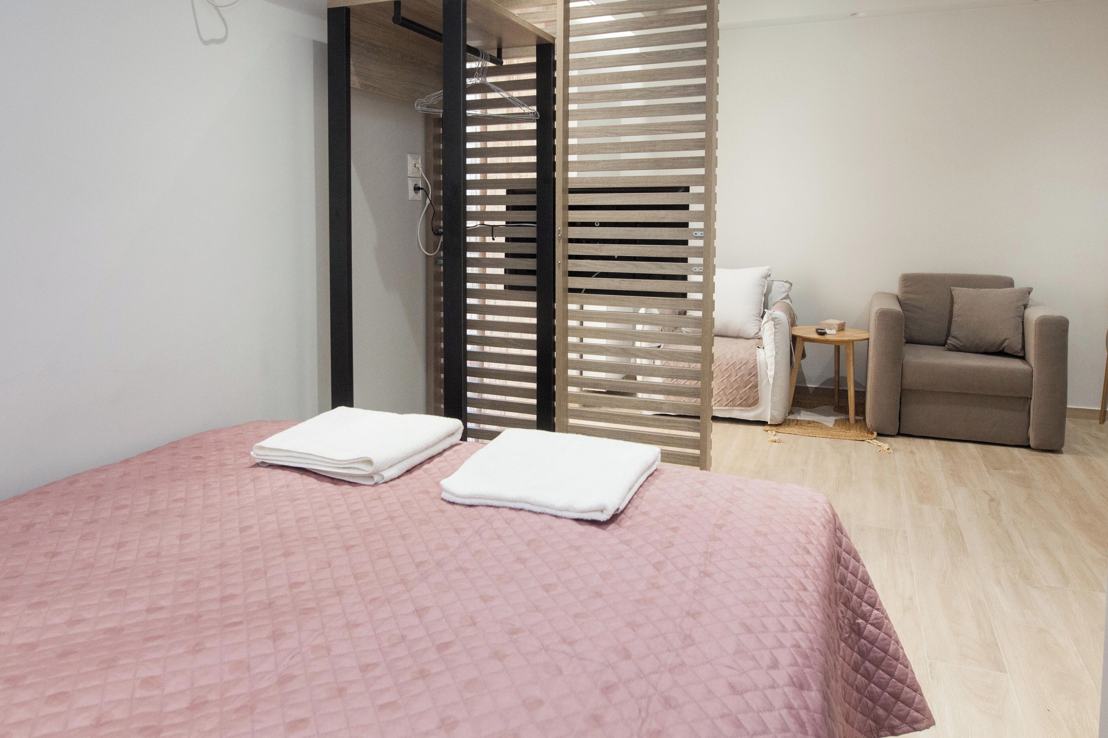 A hotel room with a bed, a chair, a small table, and a sliding door.