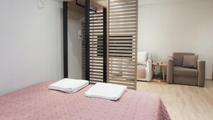 A hotel room with a bed, a chair, a small table, and a sliding door. - Petralona Gem Hotel-Style Studio Balcony (Athens)