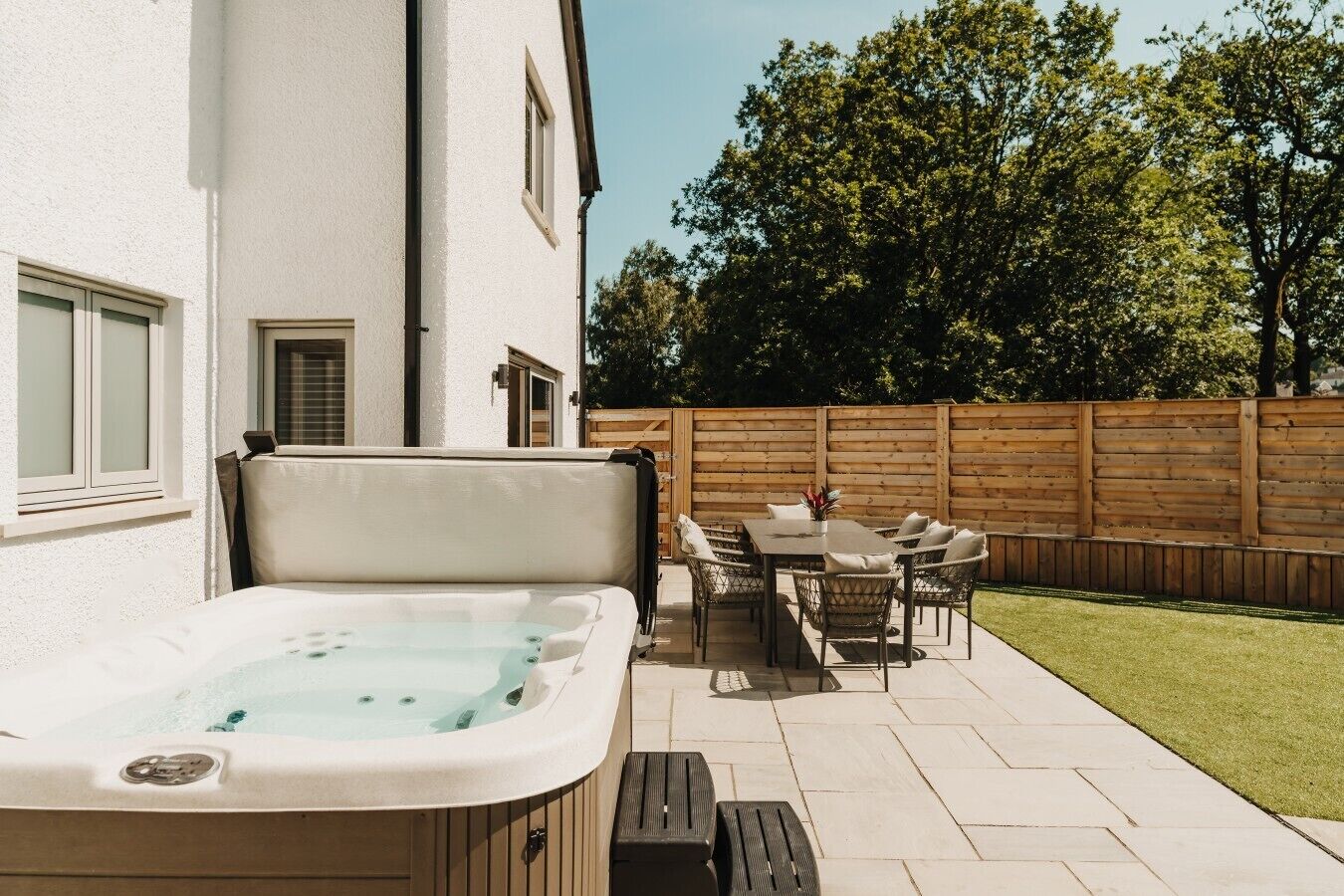 A hot tub with a table and chairs in a backyard.