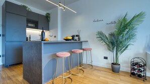 A modern kitchen with a central island, bar stools, a wine rack, and a large potted plant. - Canal Couture Navigli Luxury Retreat (Milan)
