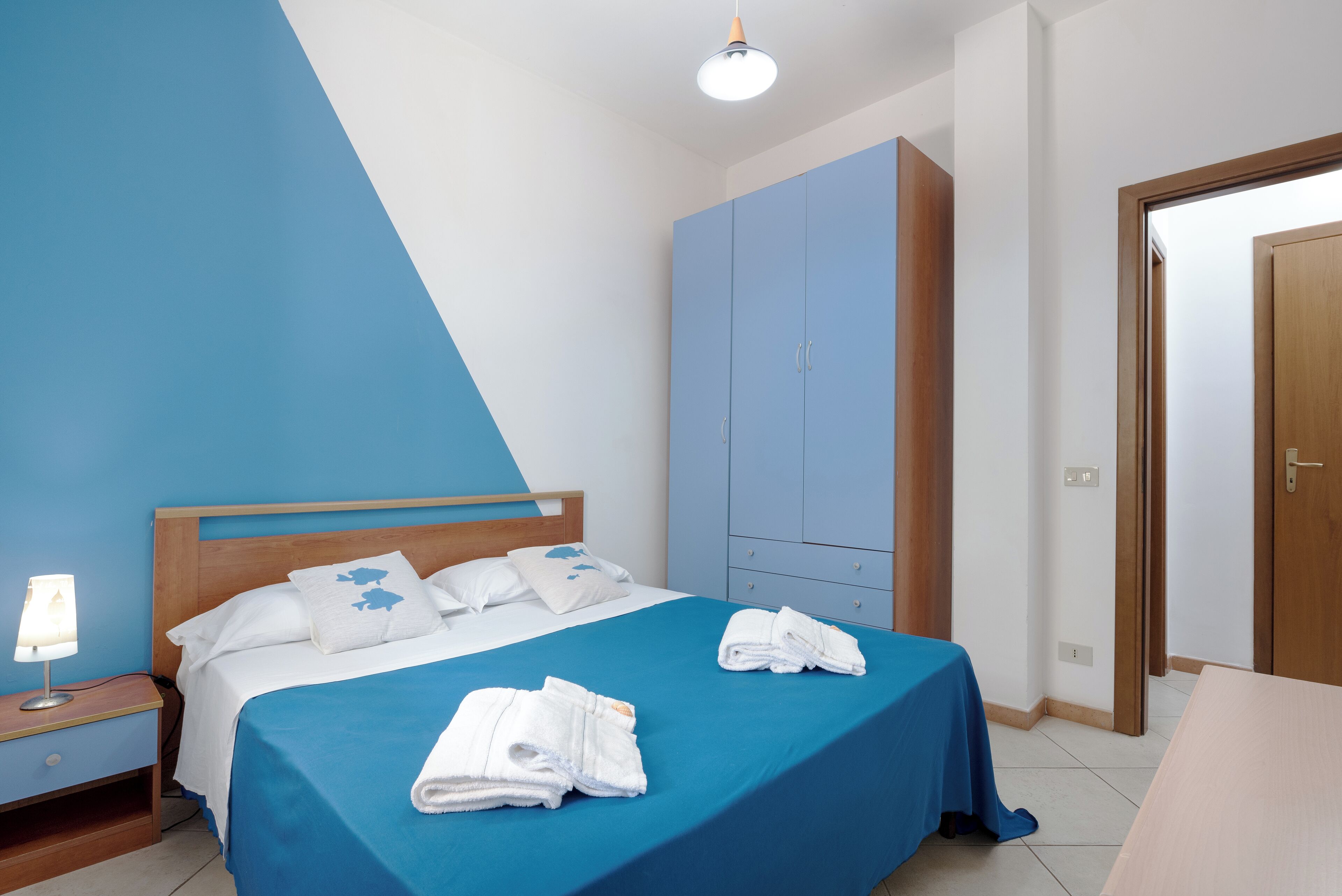 Un dormitorio con cama, mesita de noche, armario y puerta.