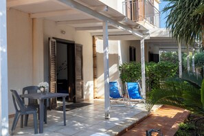 An outdoor patio area with a table and chairs, a covered seating area, and a view of the surrounding garden. - Casa Vacanza Azzurra Centro  (San Vito Lo Capo)