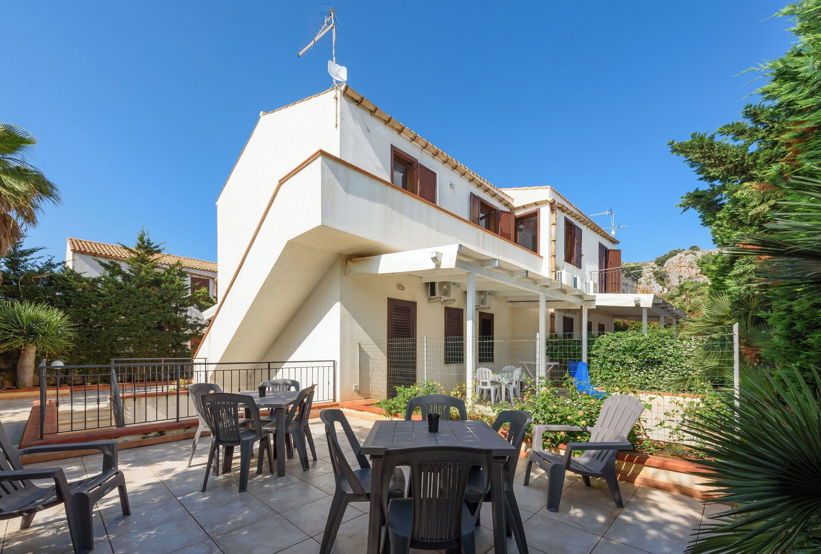 A two-story building with a patio area featuring outdoor seating.