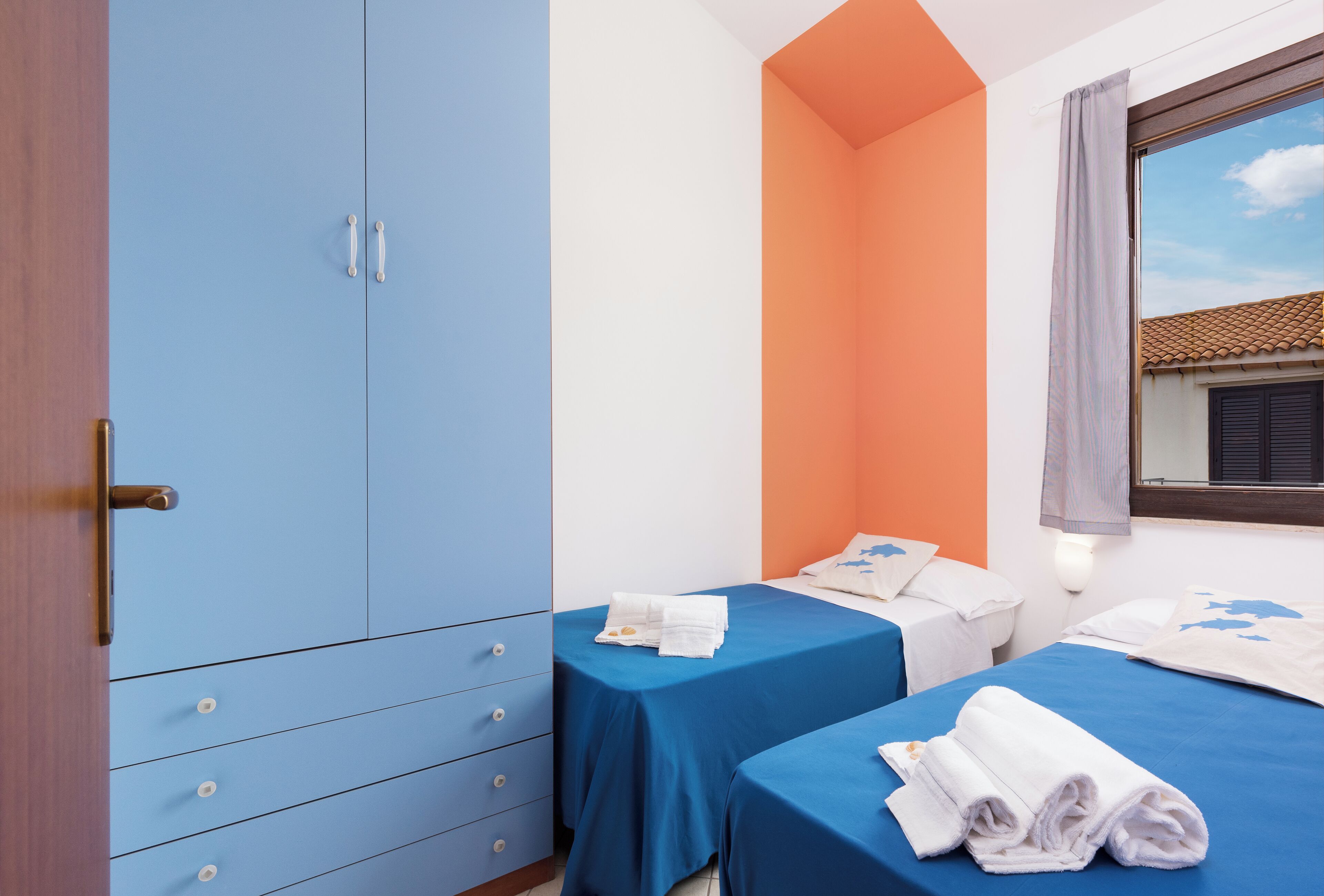 Un dormitorio con dos camas, un armario y una ventana con vistas al exterior.