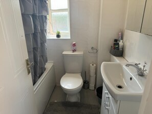 A compact bathroom with a toilet, a sink, and a window. - Luxury London Apartment With 3 Bedrooms (London)