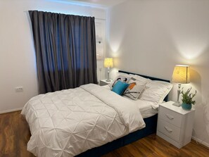 A neatly arranged bedroom with a bed, two bedside tables, a lamp, and a potted plant. - Luxury London Apartment With 3 Bedrooms (London)