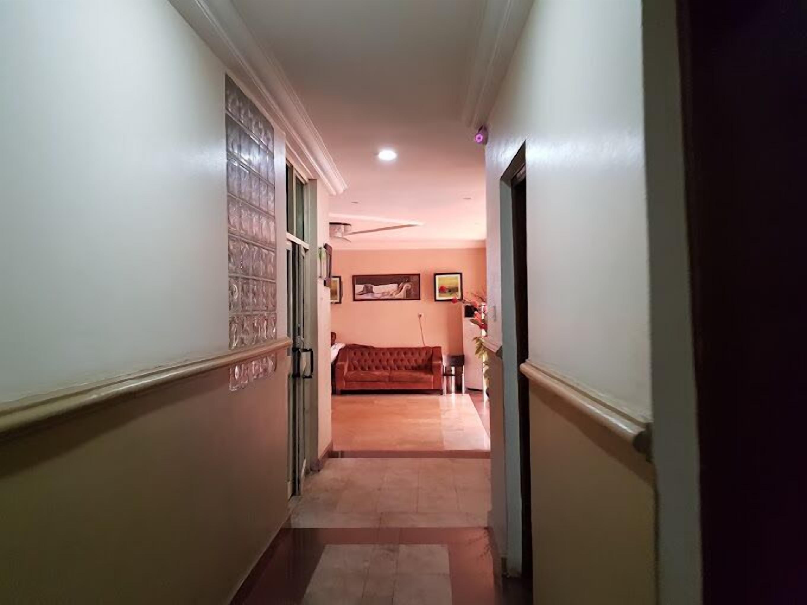 Un pasillo con un sofá rojo, una puerta con panel de vidrio y un ventilador de techo.