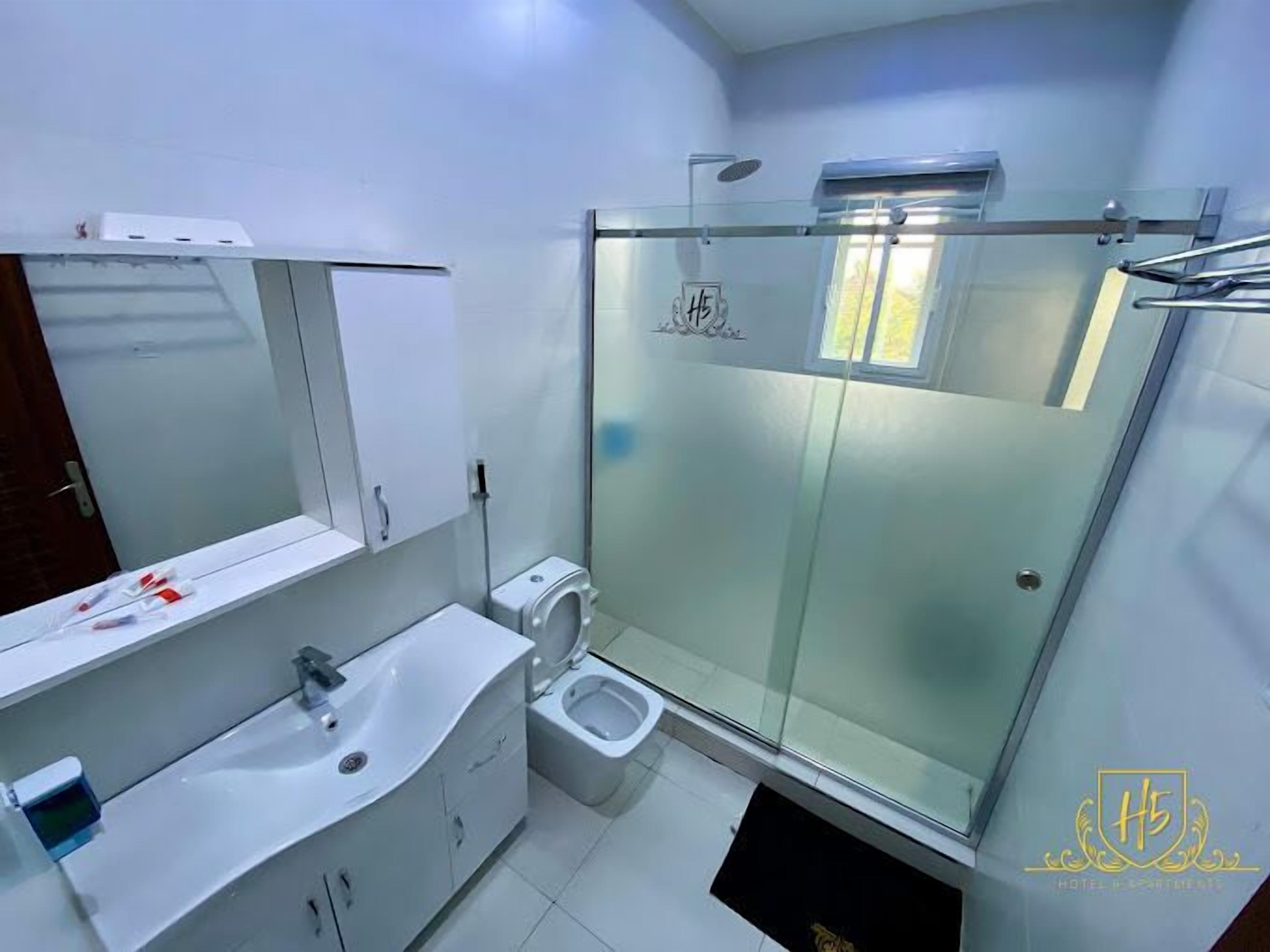 Un baño moderno con cabina de ducha de vidrio, inodoro y lavabo con espejo.