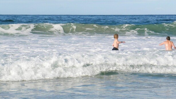 Eine Strandansicht mit zwei Personen im Wasser.
