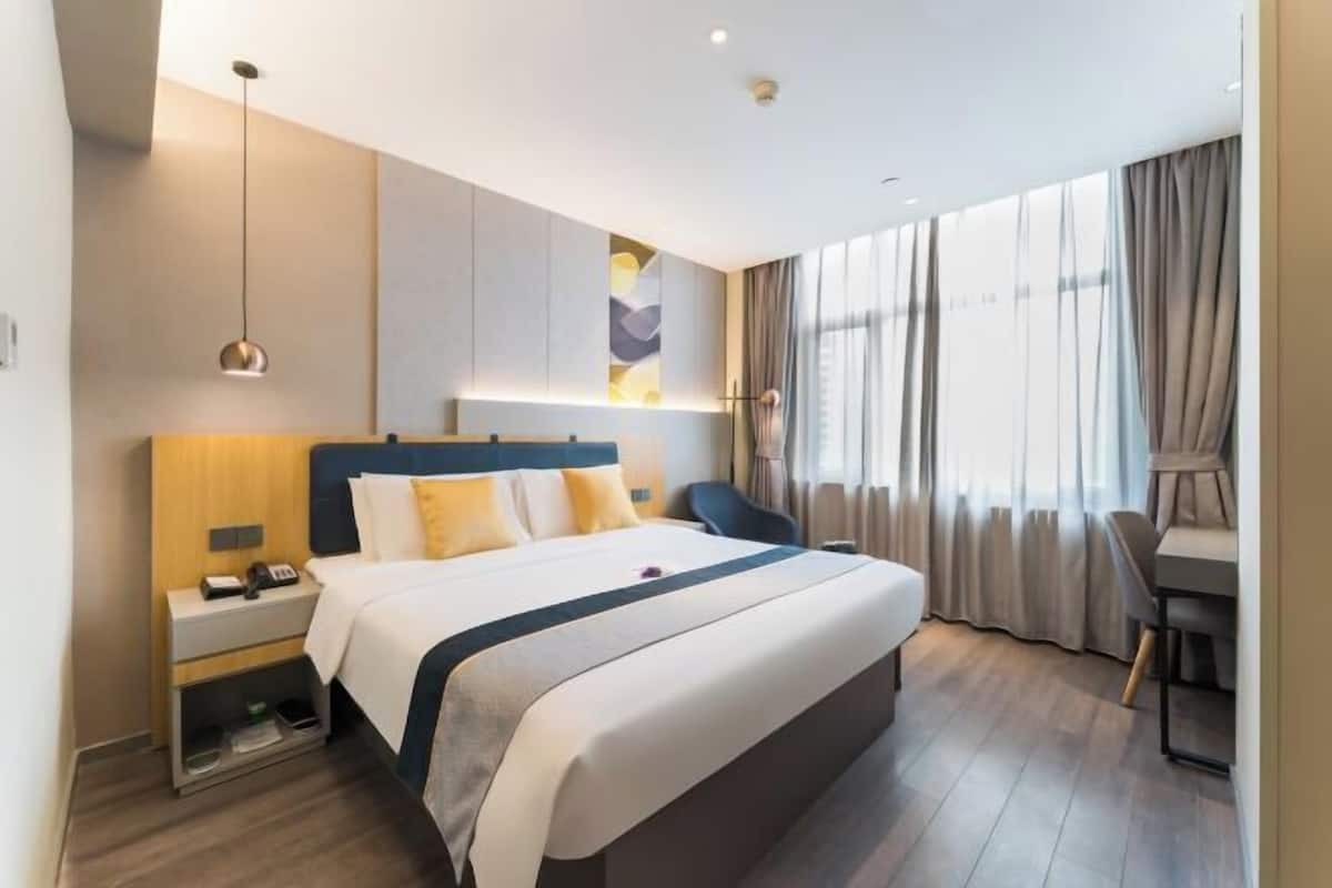 A modern hotel room with a large bed, bedside tables, a desk, and a chair.