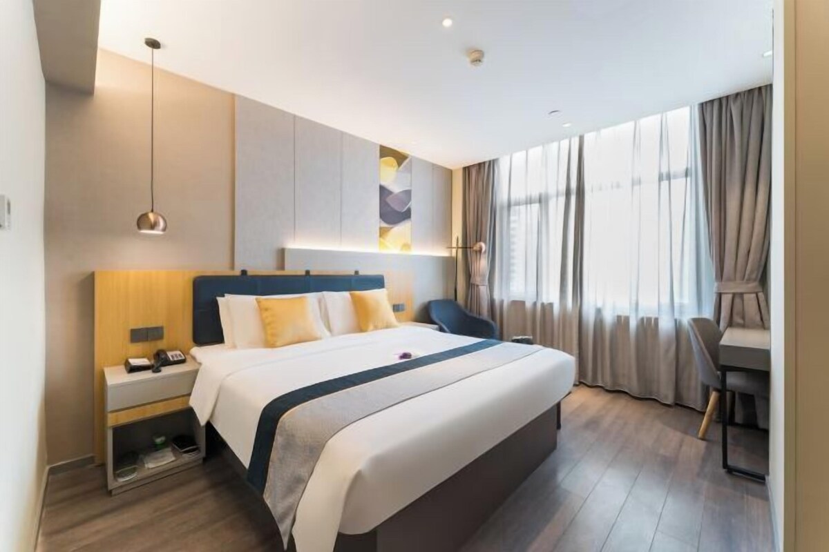 A modern hotel room with a large bed, bedside tables, a desk, and a chair.