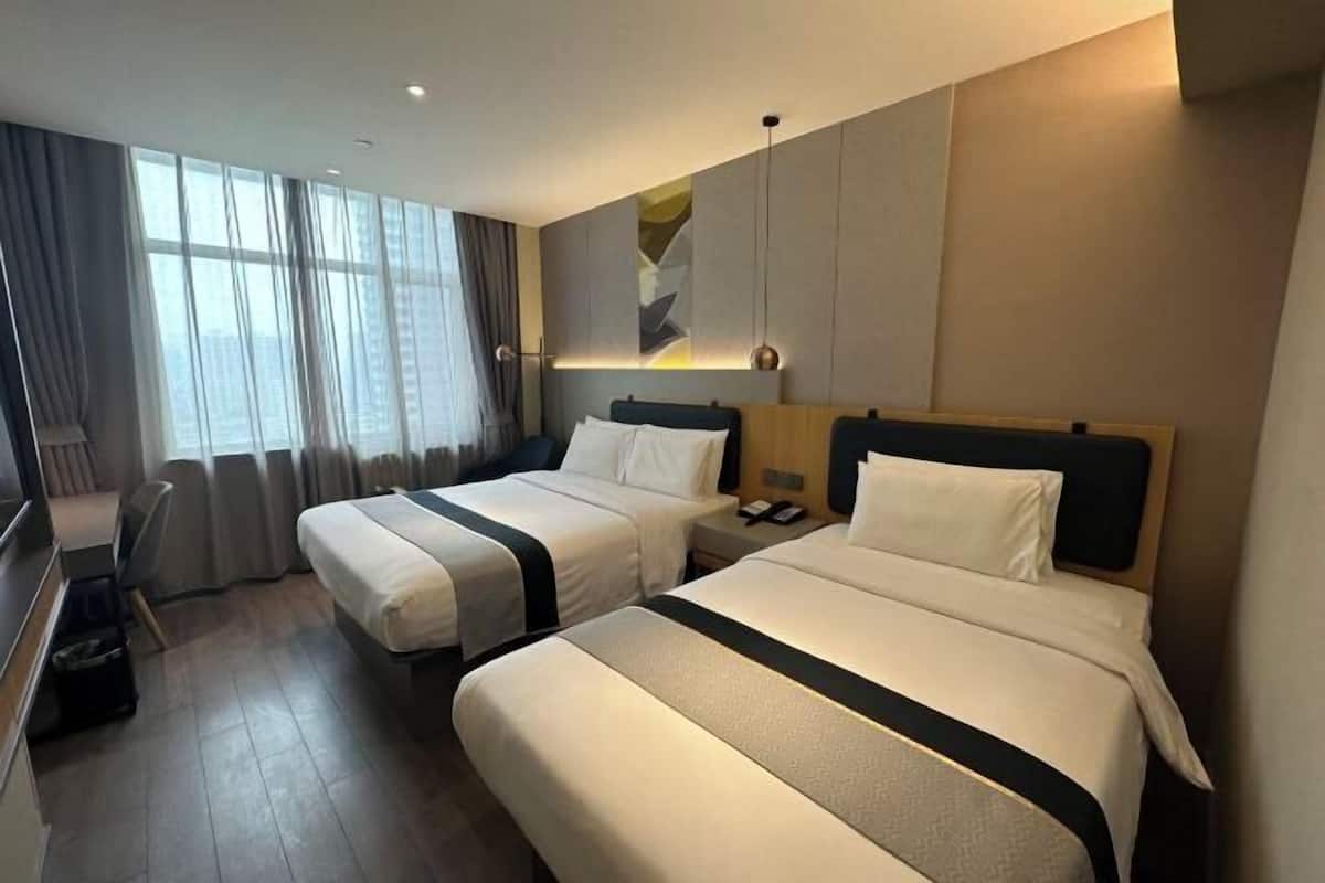 A hotel room with two beds, a desk, and a chair.
