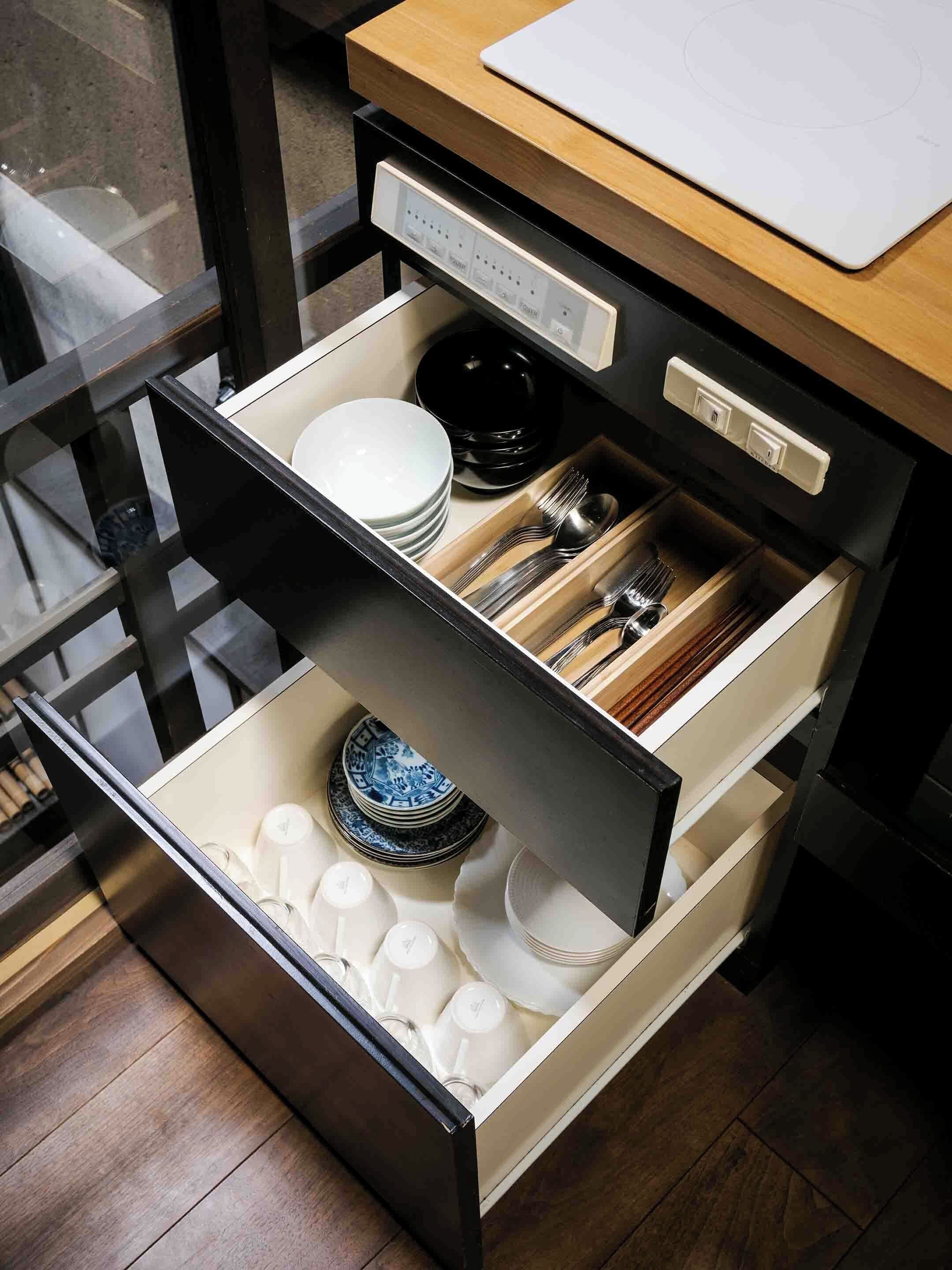 A kitchen drawer with utensils, plates, and bowls.