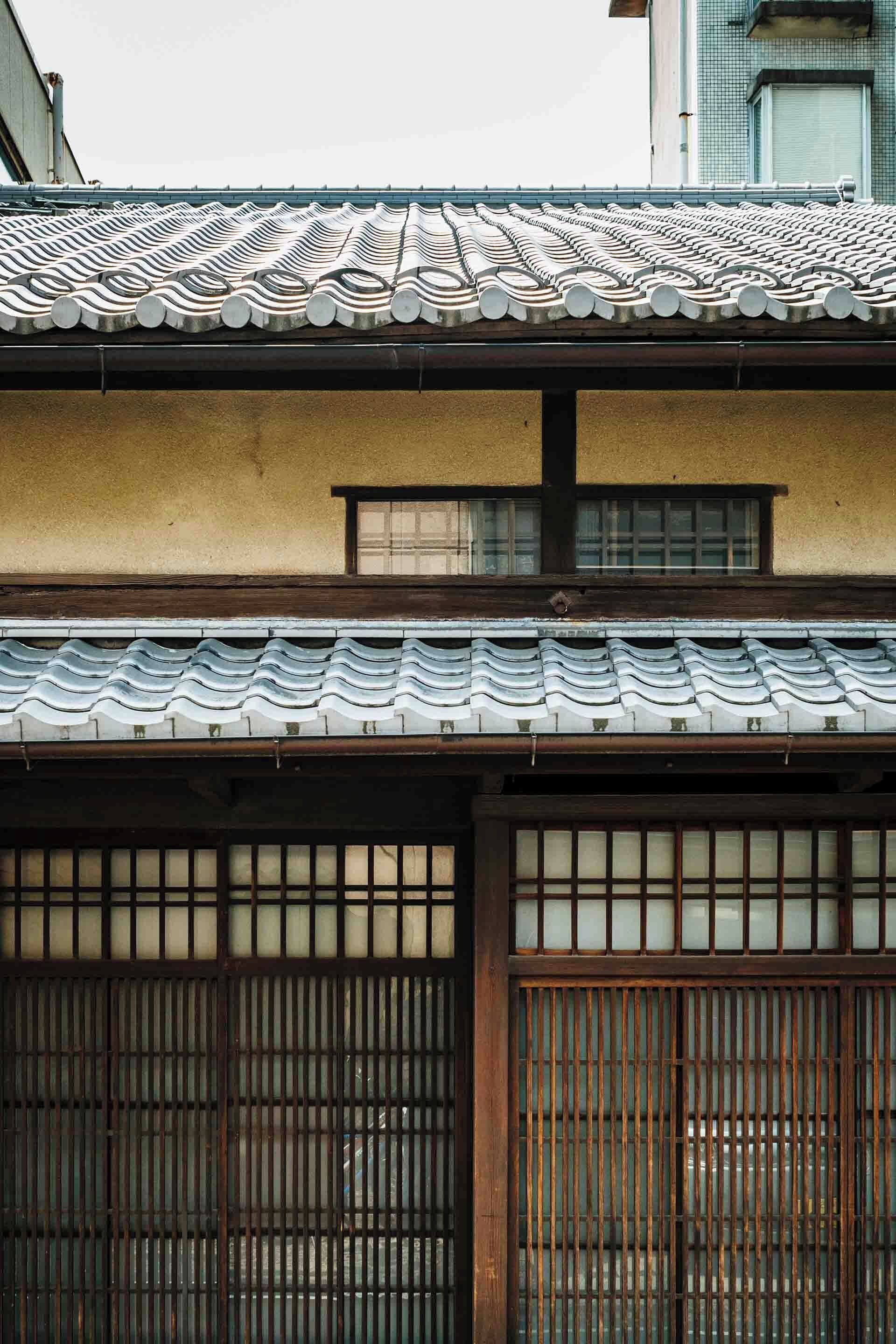 En traditionell japansk byggnad med ett tak täckt av tegelpannor och skjutdörrar av trä.