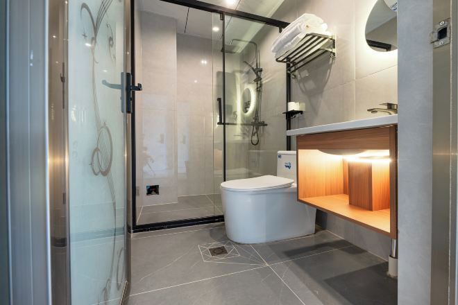 Un baño moderno con cabina de ducha de vidrio, inodoro y tocador con espejo.
