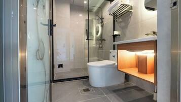 A modern bathroom with a glass shower enclosure, a toilet, and a vanity with a mirror.