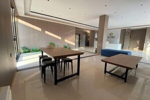 Eine moderne Hotellobby mit einer Rezeption, zwei Tischen und einer Sitzecke.