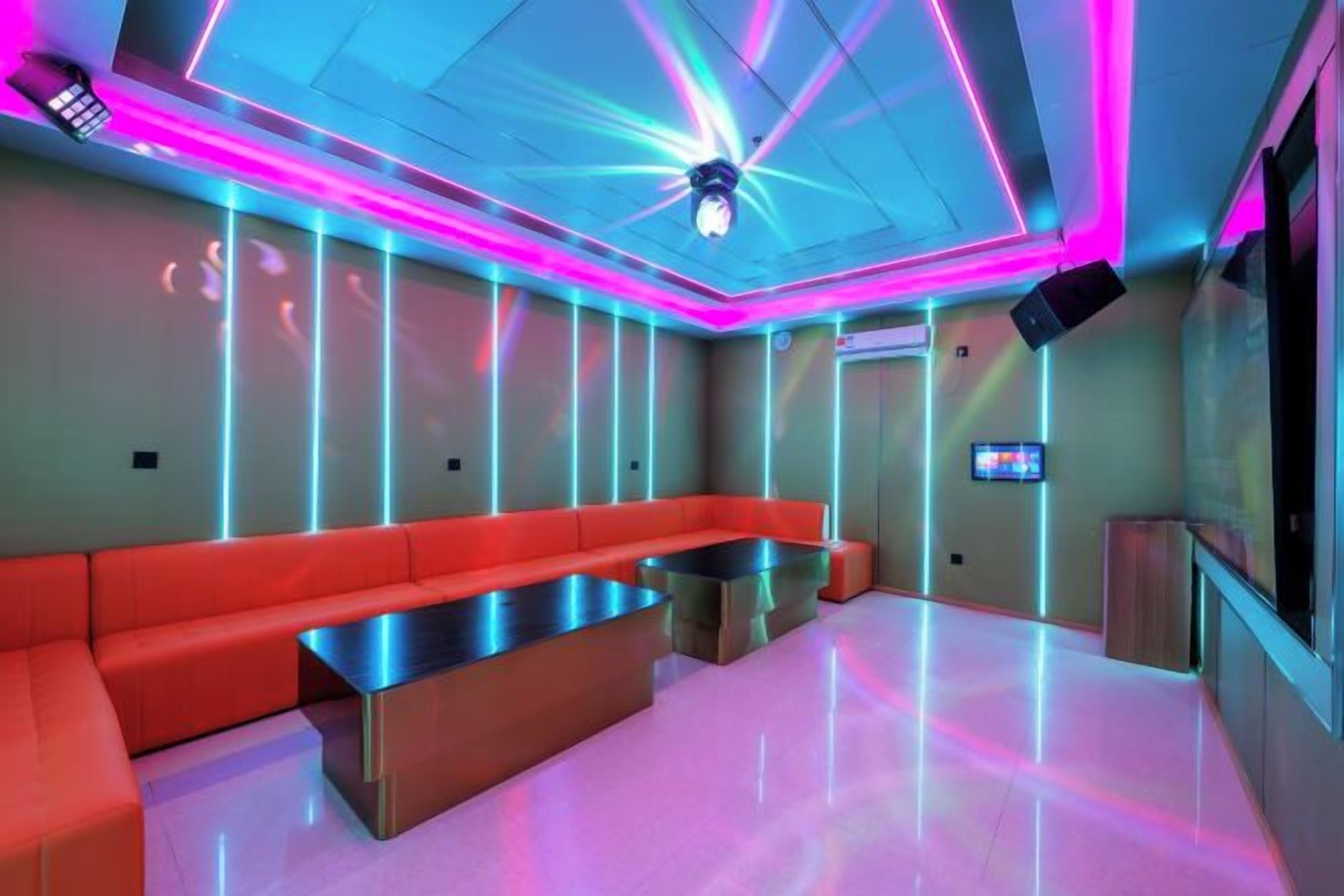 A modern lounge with a red sofa, a metallic coffee table, and a ceiling with neon lighting.