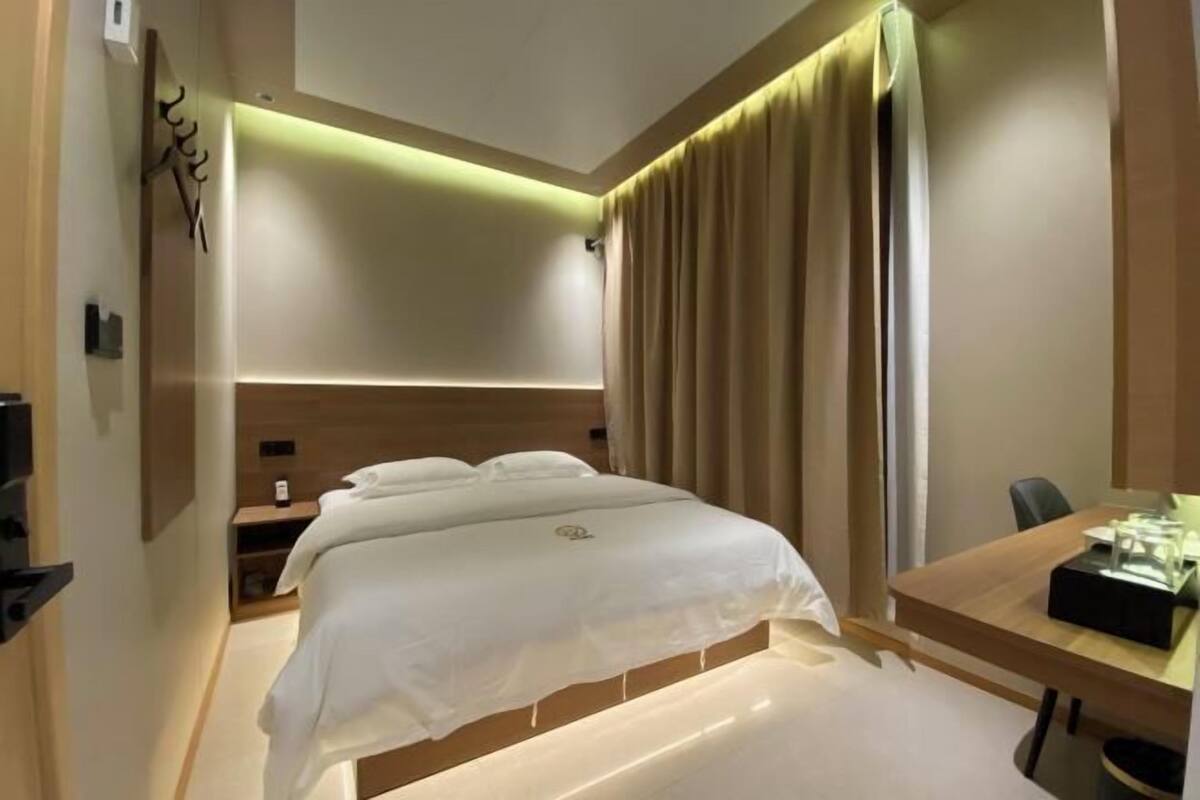 Una habitación de hotel con cama, mesita de noche y escritorio con silla.
