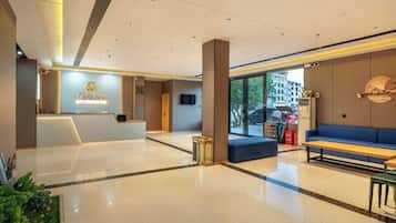 Un vestíbulo de hotel con mostrador de recepción, zona de estar y grandes ventanales.