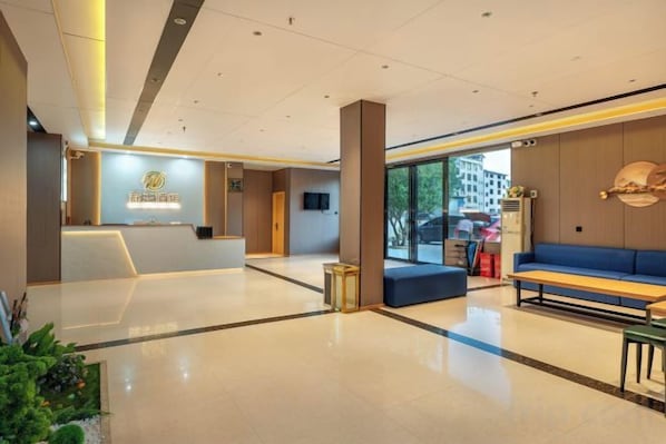 A hotel lobby with a reception desk, seating area, and large windows. - Liwang Hotel (Libo)
