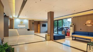 Un moderno vestíbulo de hotel con mostrador de recepción, zona de estar y ventanas amplias con vistas al exterior.