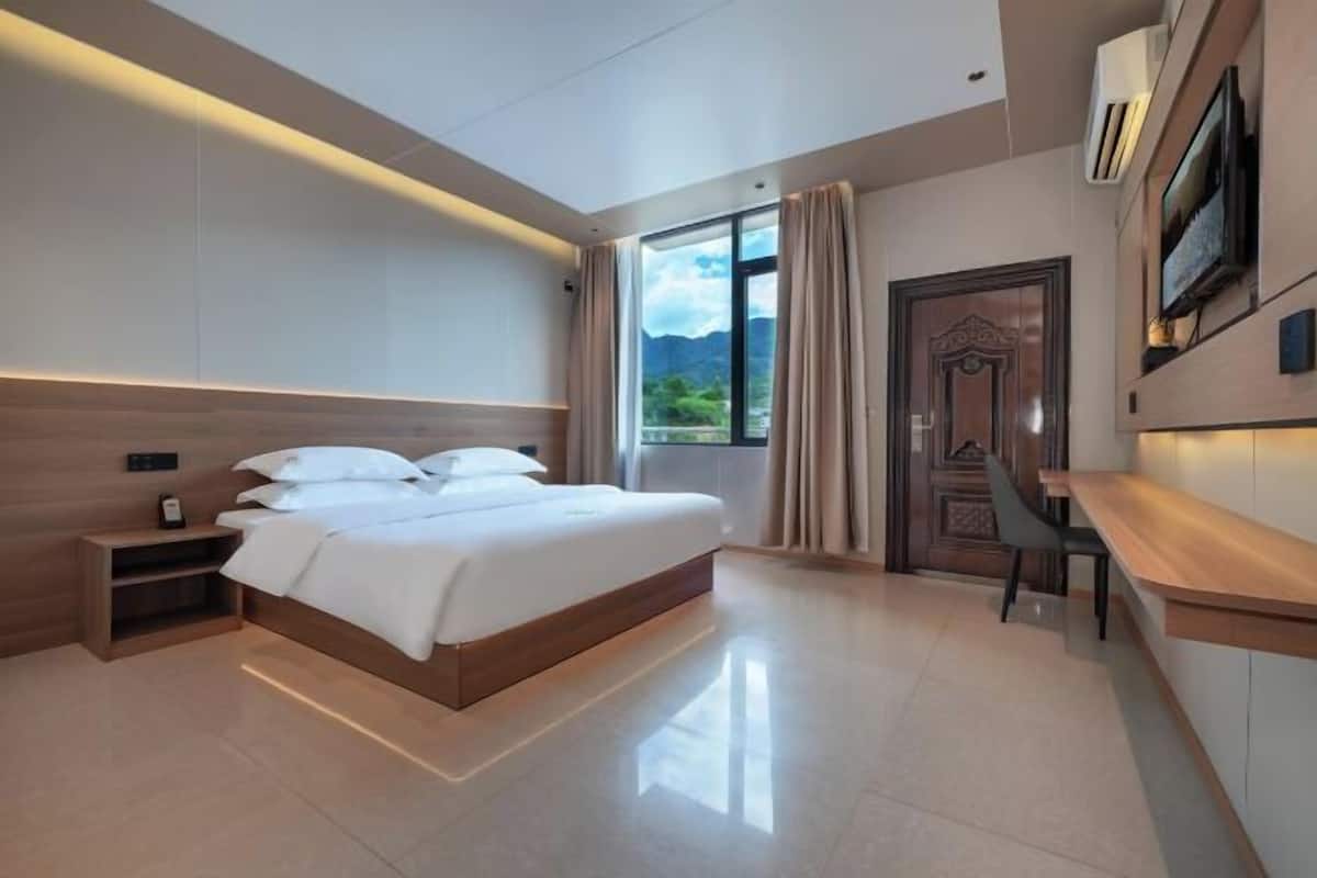 Una habitación de hotel moderna con una cama grande, mesitas de noche, un escritorio y un televisor.