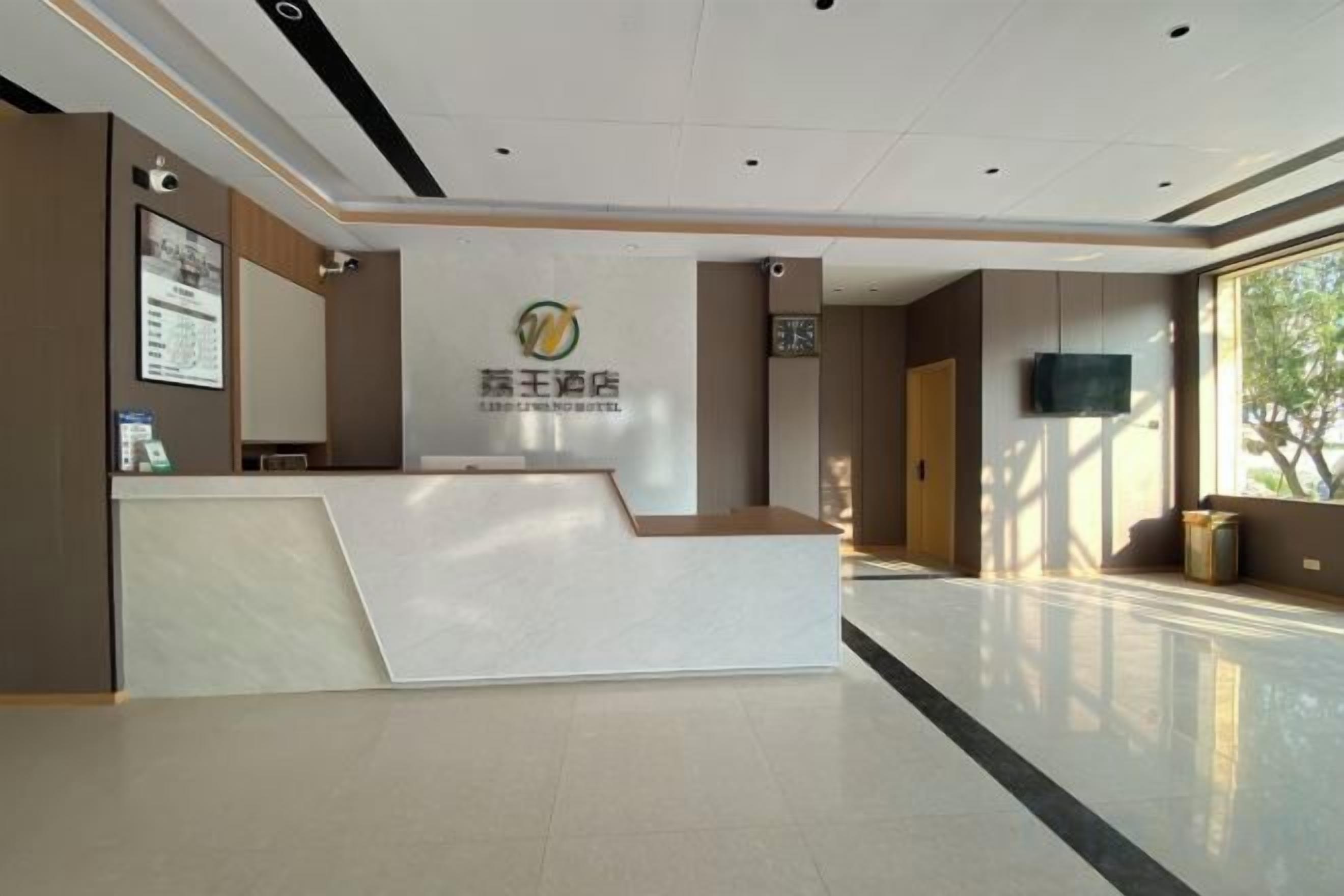 A reception area with a reception desk, a wall-mounted television, and a window providing natural light.