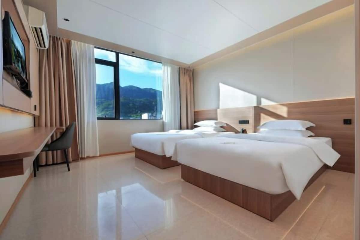 Una habitación de hotel moderna con una cama grande, un escritorio y vistas a las montañas.