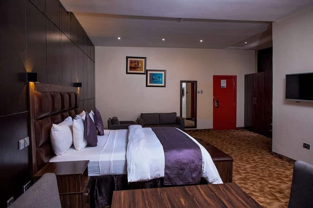 Une chambre d’hôtel avec un grand lit, un bureau, une chaise, une télévision et une porte rouge.