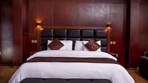A hotel room with a large bed, dark wood paneling, and a modern headboard. - Elegant Hotel by Best Western Plus  (Enugu)
