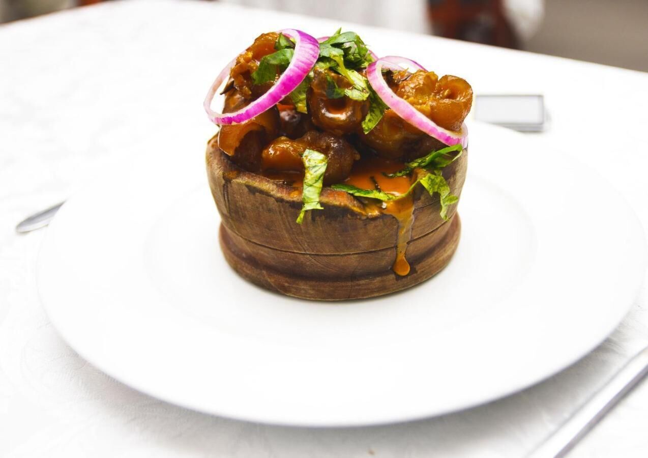 A dish with meat, vegetables, and sauce on a white plate.