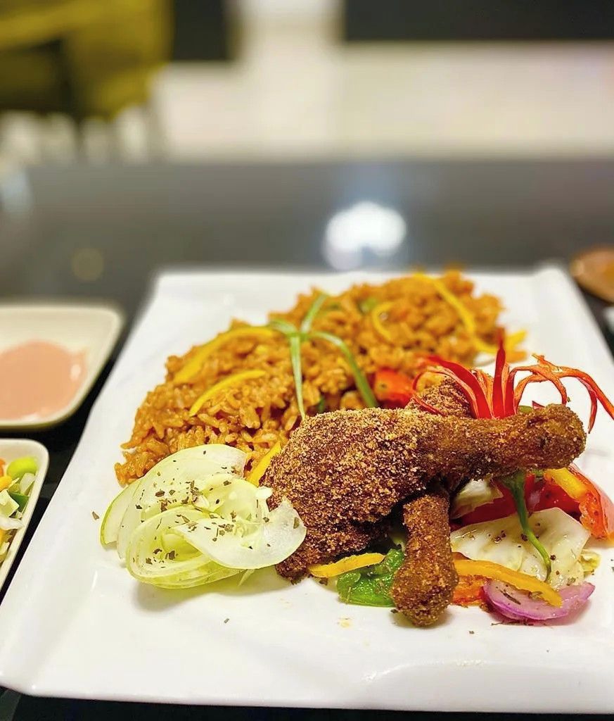 A plate of fried chicken, rice, and vegetables.