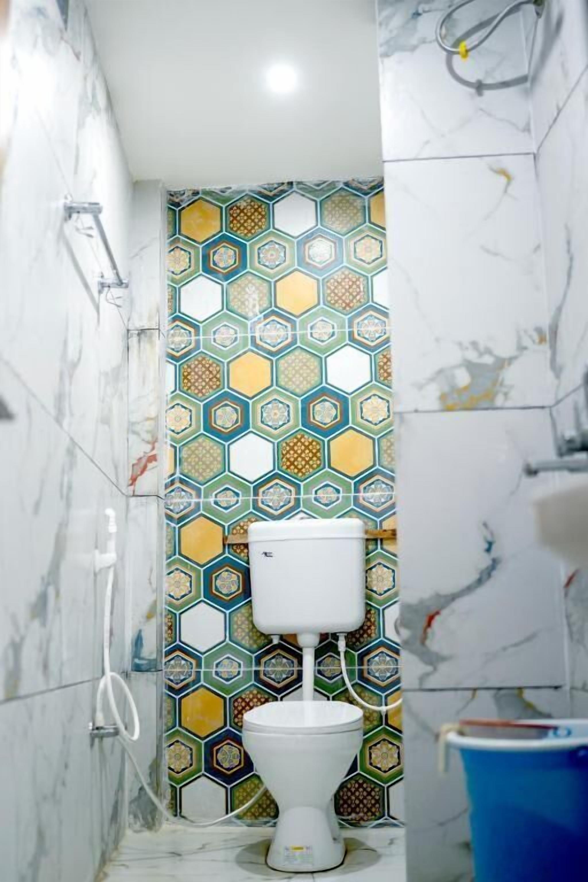 Une salle de bain avec des toilettes blanches, une douche et un seau bleu.